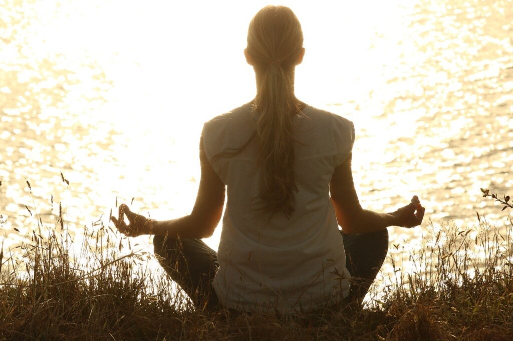 Woman meditating by water. How I Put My Mastocytosis into Remission